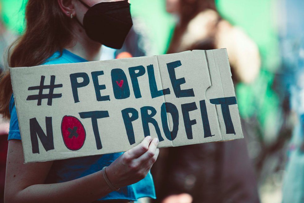 a woman holding a sign that says people not profits
